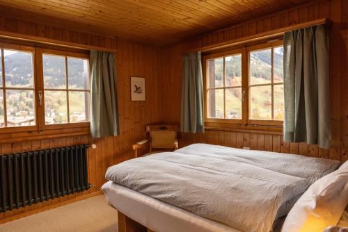 a bedroom with a bed in a room with windows at Chalet Egghus Klosters in Klosters