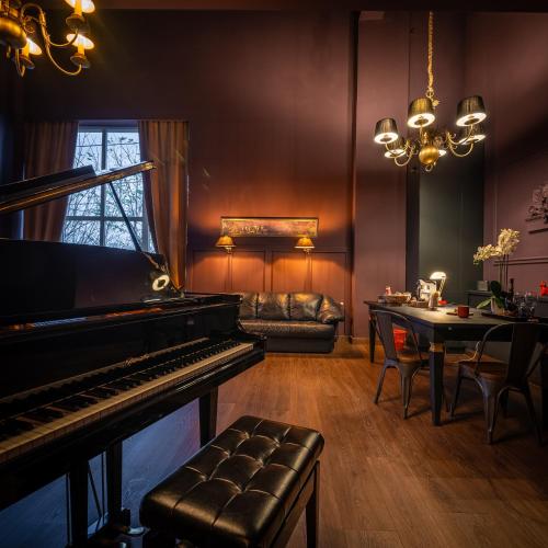 a living room with a piano and a table at Hotel Cocó in Timişoara
