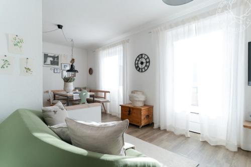 ein Wohnzimmer mit einer grünen Couch und einer Uhr an der Wand in der Unterkunft Appartements Lärchmoos in Ramsau am Dachstein