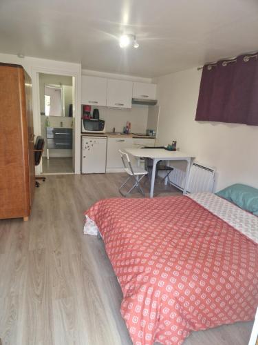 a bedroom with a bed and a kitchen with a table at Studio à Orsay à 5 min du RER B Le Guichet in Orsay