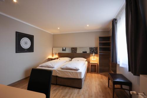 a bedroom with a bed and two tables and a window at Arthotel ANA Flair in Nördlingen