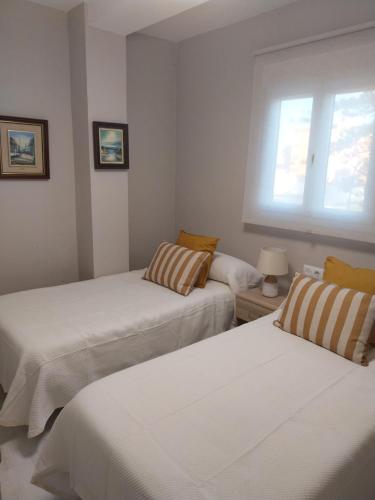 two beds in a room with a window at PLAYA LAS PILETAS-CALZADA in Sanlúcar de Barrameda