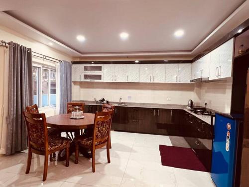 eine Küche mit einem Holztisch und Stühlen sowie einem Tisch und einer Küche in der Unterkunft A beautiful cozy modern house. in Siddharthanagar