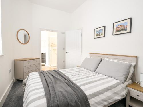 a white bedroom with a bed and a mirror at Apartment 5 Victoria House in Lyme Regis