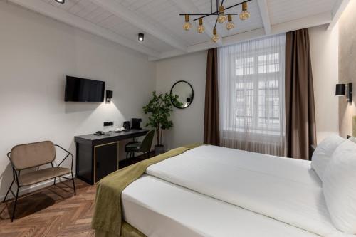 a bedroom with a bed and a desk and a chair at Konventa Sēta Hotel Keystone Collection in Rīga