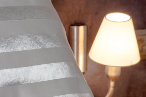 a lamp next to a bed with a white sheet at Triada Hotel in Sofia