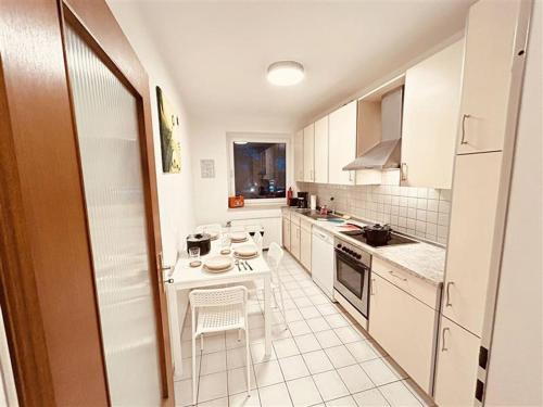 eine kleine weiße Küche mit einem Tisch und Stühlen in der Unterkunft Fully eqiupped apartment in Winsen (Luhe) in Winsen