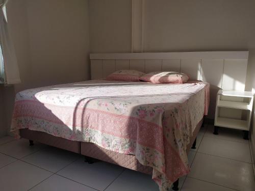 a bed with a pink blanket and two pillows on it at Kitnet ótima localização em Garanhuns (103) in Garanhuns