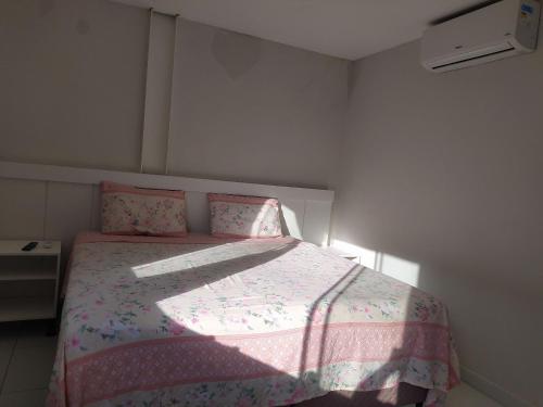 a bedroom with a bed with a pink comforter at Kitnet ótima localização em Garanhuns (103) in Garanhuns