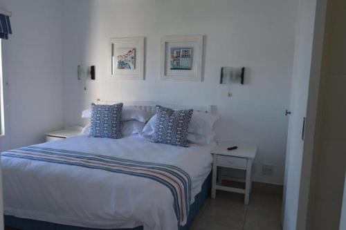 a white bedroom with a bed with blue pillows at 358 Kaliva - Club Mykonos in Langebaan