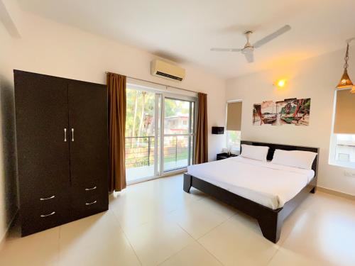a bedroom with a bed and a large window at Rainforest Enclave, Arpora - 10 mins to Baga beach in Arpora