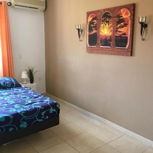 a bedroom with a bed and a picture on the wall at Villa Unique in Willemstad