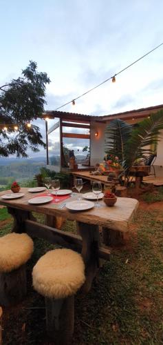 una mesa de picnic con copas de vino y taburetes. en Cabana Canal do Infinito, en Domingos Martins