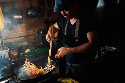 a woman cooking food in a wok in a kitchen at 翠安儂風旅 in Taitung City