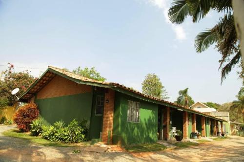 a green building with a palm tree in front of it at Chacara Descanso do Rei in Vinhedo