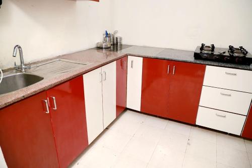 a kitchen with red and white cabinets and a sink at Greenleaf Apartment and Suites, Chittaranjan Park in New Delhi