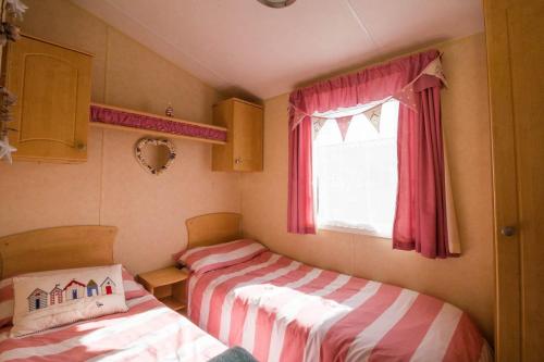 two beds in a small room with a window at Spacious 8 Berth Caravan At Heacham Beach Holiday Park In Norfolk Ref 21027b in Heacham