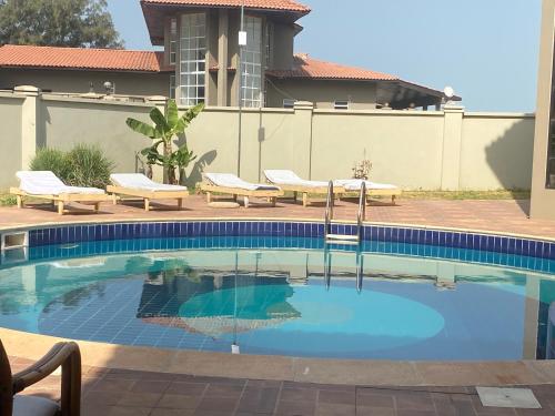 uma piscina com duas espreguiçadeiras ao lado de uma casa em Cape Residence em Bakau