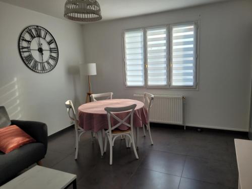 ein Esszimmer mit einem Tisch, Stühlen und einer Uhr in der Unterkunft Appartement F3 de 60M² à 20 minutes de Paris. in Yerres