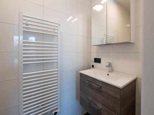 a white bathroom with a sink and a mirror at Spacious waterfront apartment in Arnemuiden