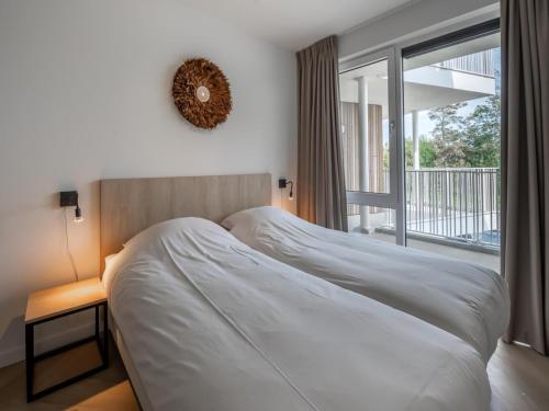 a white bed in a bedroom with a window at Spacious waterfront apartment in Arnemuiden