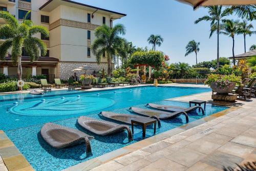 a pool at a hotel with lounge chairs and palm trees at Ko Olina Beach Villas O505 in Kapolei