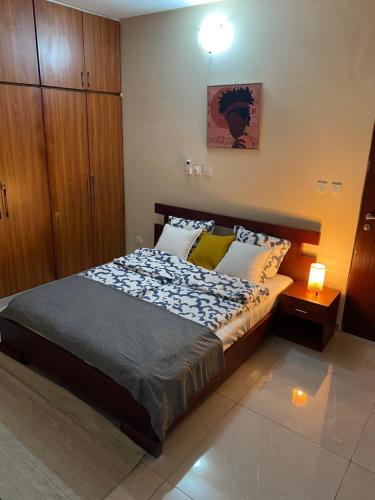 a bedroom with a bed and a wooden cabinet at Appart Neuf et Lumineux à 2 Pas d'Angre Chu in Abidjan