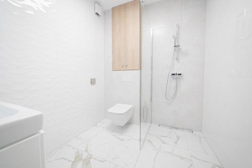 a white bathroom with a shower and a toilet at VacationClub - Zdrojowa 7 Apartament 5 in Duszniki Zdrój