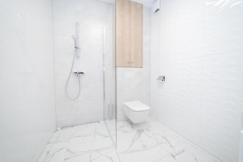 a white bathroom with a shower and a toilet at VacationClub - Zdrojowa 7 Apartament 3 in Duszniki Zdrój