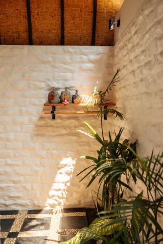 a wall with a shelf with vases and a plant at Hani Hideaway in Gili Air