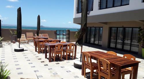 Ramena Beach Hotel في Ramena: صف من الطاولات والكراسي الخشبية على الفناء