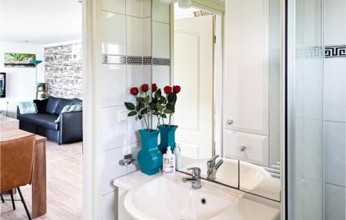 een badkamer met een wastafel met rode bloemen in een blauwe vaas bij Amazing Home In Molenschot With House Sea View in Molenschot