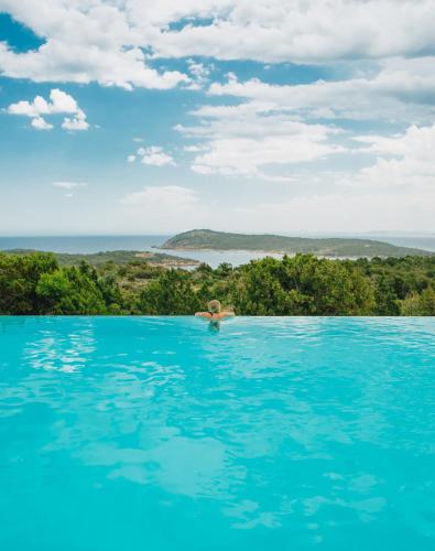 a person in a swimming pool in the water at Résidence Les Terrasses de Rondinara in Bonifacio