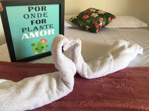een witte handdoek op een bed met een bord bij Pousada da Sami in Barra de São Miguel