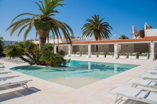 a swimming pool with palm trees and lounge chairs at Ostuni a Mare in Ostuni