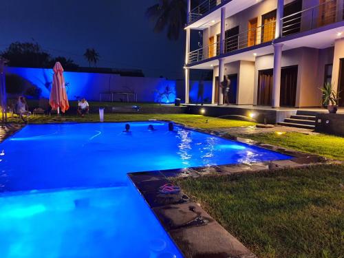 a swimming pool in front of a building at night at HOTEL GANI in Manjacaze