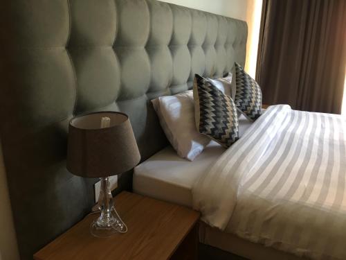 a bed with a headboard and a lamp on a table at HOTEL GANI in Manjacaze