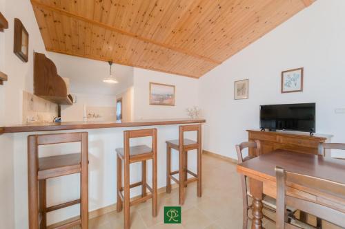 a kitchen with a bar with stools and a tv at Albatros in Capoliveri