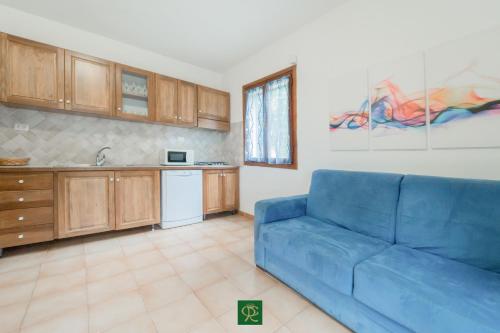 a living room with a blue couch and a kitchen at Albatros in Capoliveri