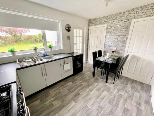 a kitchen and dining room with a table and a window at South Stack Bungalow in Holyhead