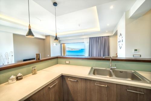 a kitchen with a sink and a large window at Golden View Luxury Villa Platanias in Plataniás