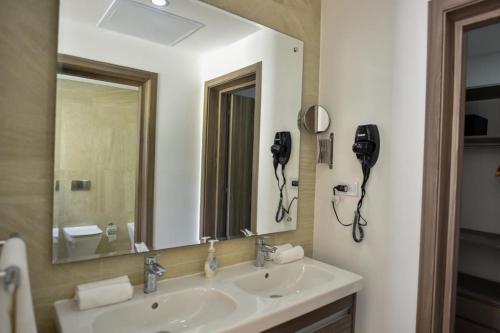 ein Badezimmer mit einem Waschbecken und einem großen Spiegel in der Unterkunft Hard Rock at Cana Pearl by Unwind Properties in Punta Cana