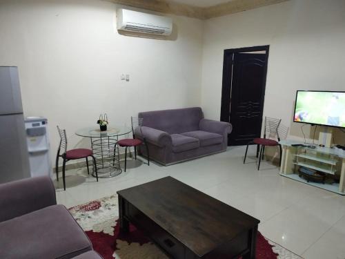 - un salon avec un canapé, une table et une télévision dans l'établissement العين الهيلي مصباح بيت 8, à Al-Aïn