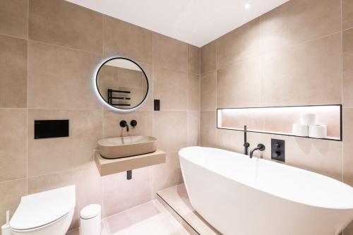 a bathroom with a tub and a sink and a mirror at The Maida Vale in London