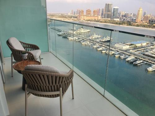 a balcony with two chairs and a view of a harbor at Seaside Serenity Perfect Beachfront Holiday Haven in Dubai