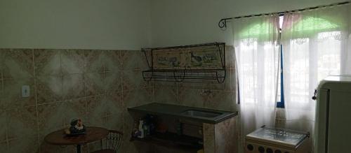uma cozinha com um lavatório, uma mesa e uma janela em casas temporada em Tiradentes do mazinho em Tiradentes