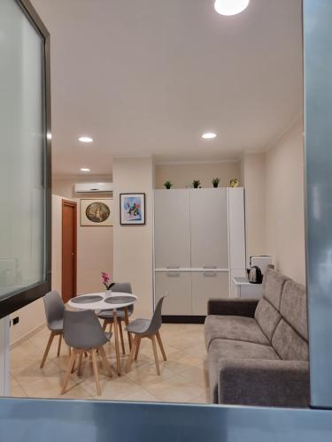 Loft Magna Grecia Reggio Calabria Centro Storico في ريجّو دي كالابريا: غرفة معيشة مع أريكة وطاولة وكراسي