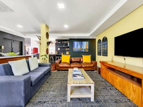 a living room with a couch and a flat screen tv at Spacious family Apartment Near Beach with Inverter in Cape Town