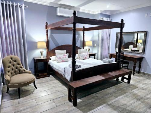 1 dormitorio con cama con dosel y silla en 2 Owls Guesthouse, en Potchefstroom