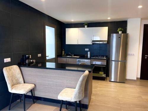 uma cozinha com um balcão com 2 cadeiras e um frigorífico em Luxurious Golf & Sea View Beach Apartment with Pool Access - Cocon de Taghazout Bay em Taghazout